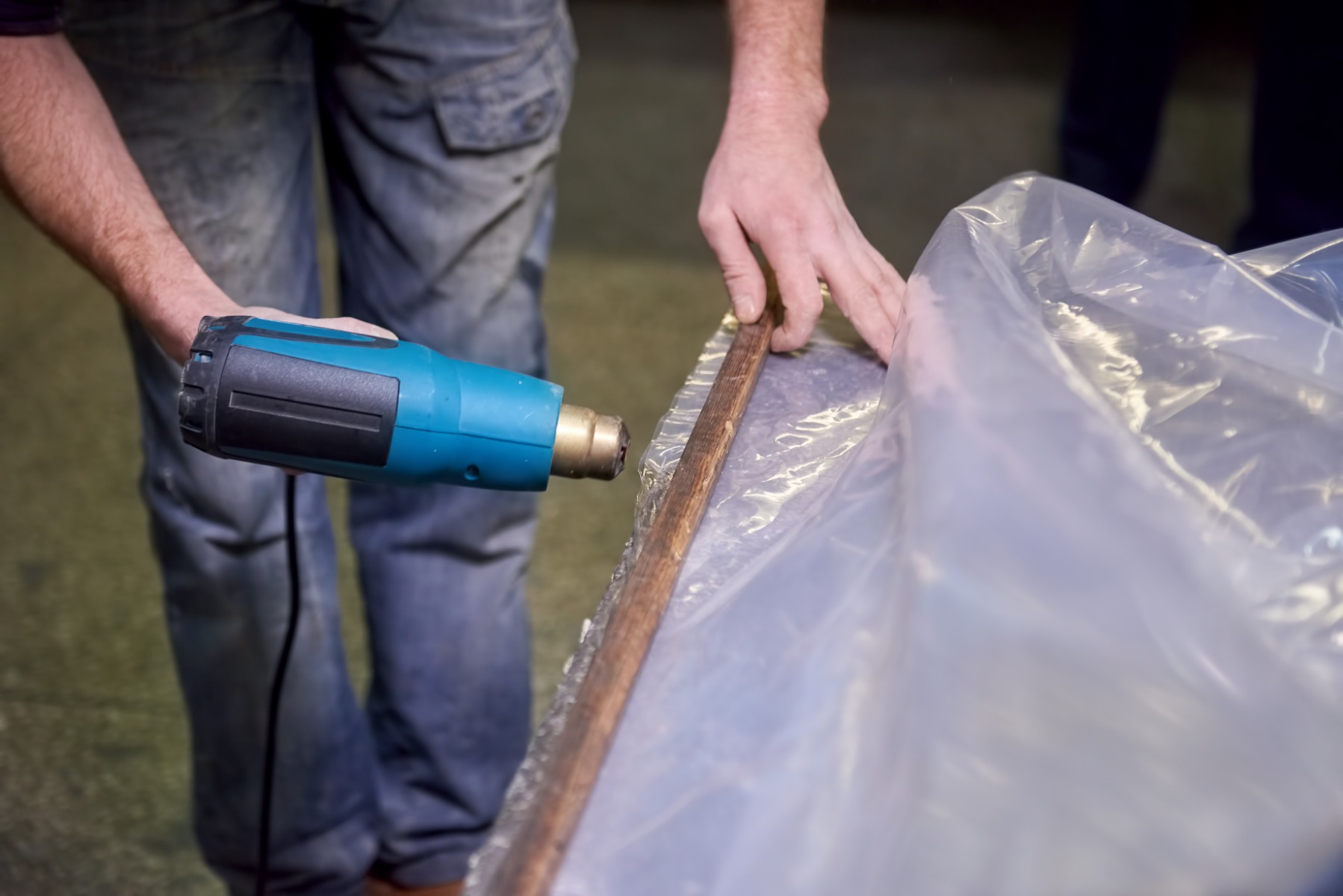 A worker using a heat gun on shrink wrap.